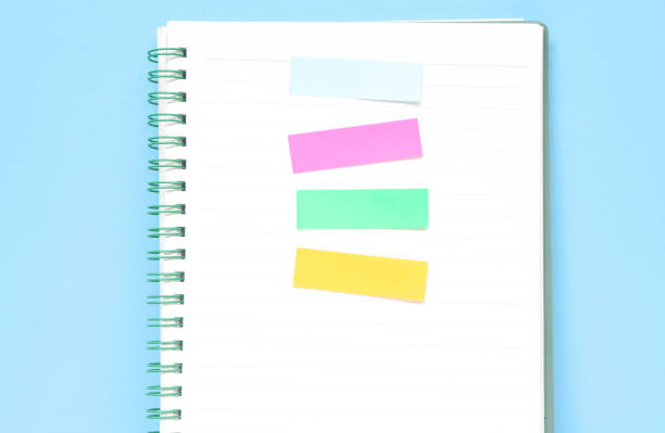 istock Four colored markers in a notebook on a wooden table. Colorful post paper notes or bookmarks on gray background. Journaling and office desk concept 1987455057