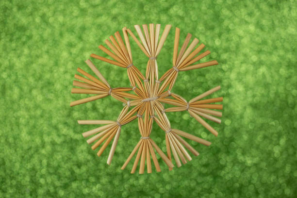 Christmas star snowflake decoration made with golden straws and thread on green glitter background, soft focus close up