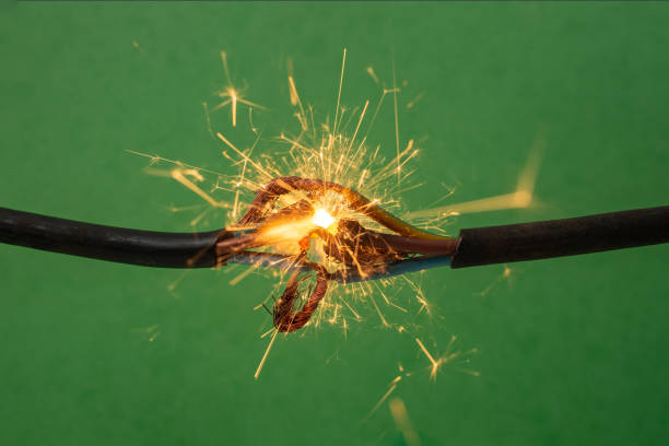 istock Sparks explosion between electrical cables, on green background, fire hazard concept, soft focus close up 1987468119