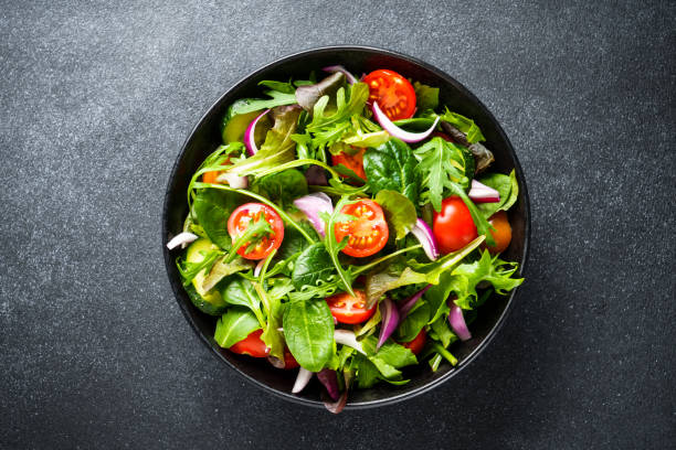istock Salad in black bowl at dark background. 1987498676