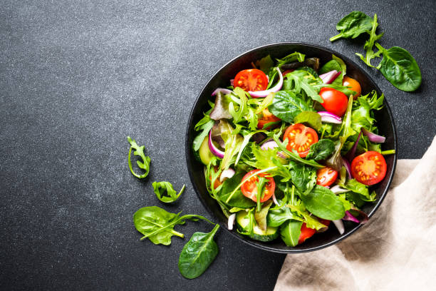 istock Salad in black bowl at dark background. 1987498693