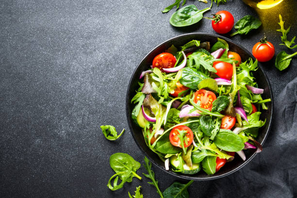 istock Green Salad with salad leaves and vegetables at black background. 1987498696