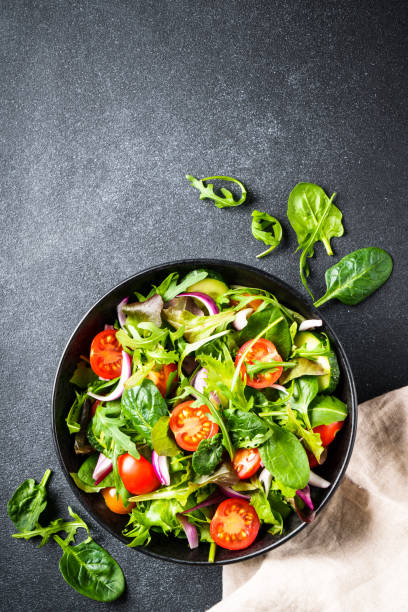 istock Salad in black bowl at dark background. 1987498718