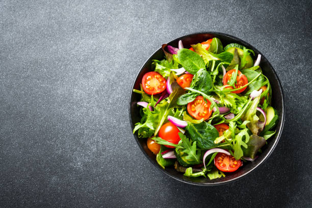 salad in black bowl at dark background. - salade composée photos et images de collection
