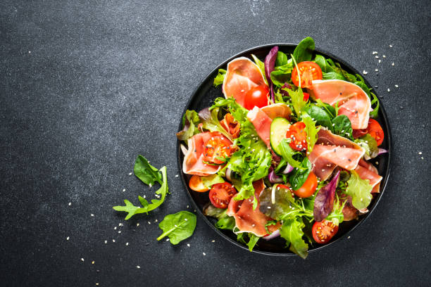 istock Salad in black bowl at dark background. 1987499258