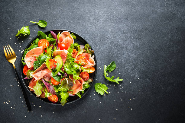 istock Salad in black bowl at dark background. 1987499652