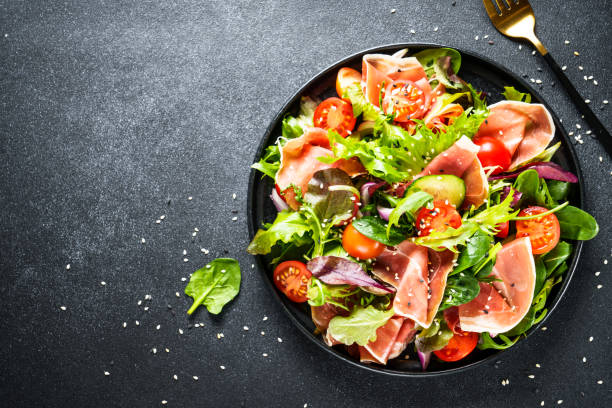 istock Salad in black bowl at dark background. 1987499773
