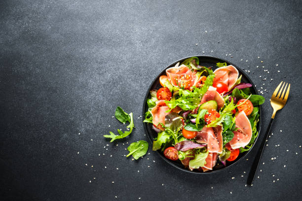 istock Salad in black bowl at dark background. 1987499775