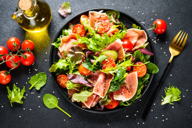 istock Salad in black bowl at dark background. 1987499783