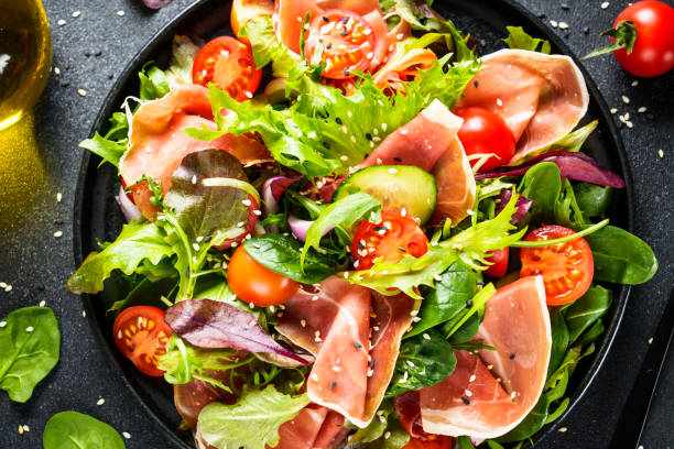 istock Green vegetable salad with snoked ham and sesame. 1987499796