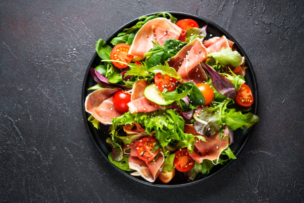 istock Salad in black bowl at dark background. 1987499804