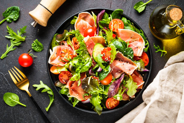 istock Salad in black bowl at dark background. 1987499805