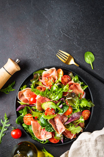 istock Salad in black bowl at dark background. 1987500321