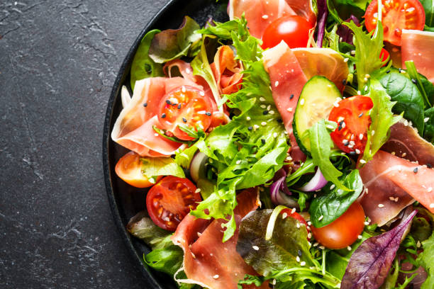 istock Green vegetable salad with snoked ham and sesame. 1987500329
