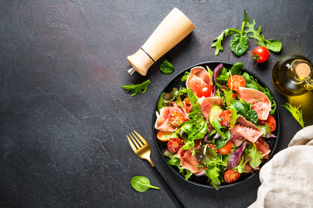 istock Salad in black bowl at dark background. 1987500341