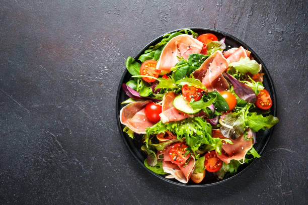 istock Fresh salad with jamon, green salad leaves and tomatoes. 1987502044