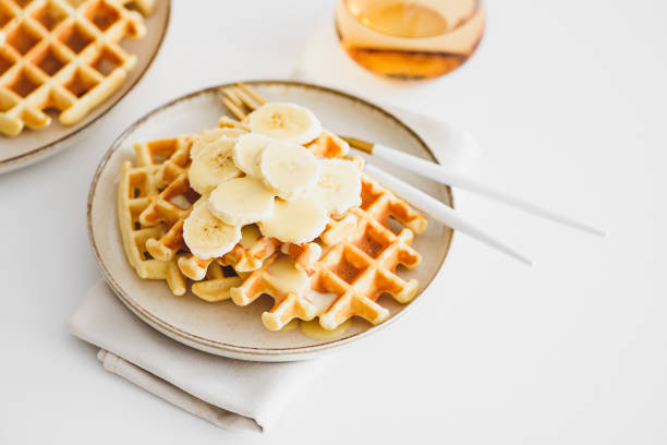 istock Belgian waffles with banana and condensed milk on white table. Top view 1987503670