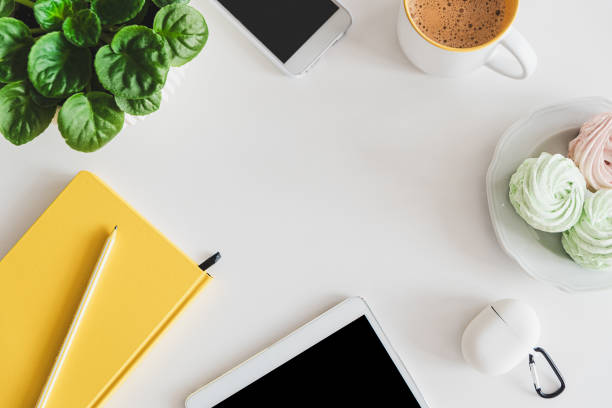 Mock-up with tablet, smartphone, notebook, coffee cup, food and plant on white table. Top view. Flat lay