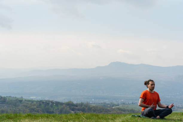 Young man do yoga on the mountain peak
