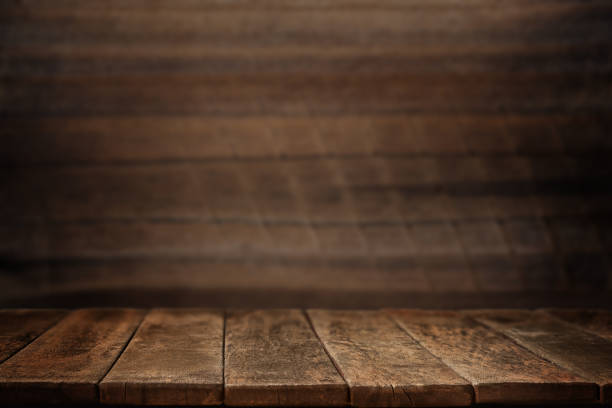 istock Empty wooden table against a dark wooden wall 1987525423