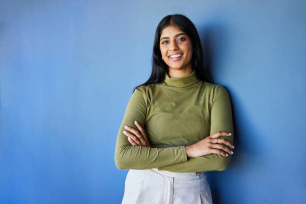 istock Young businesswoman smiling while standing against a blue office wall 1987557839