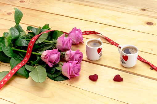 Stock photo showing an illuminated love sign, with the word 'LOVE' being spelt out by individual letters lit by bright white light bulbs. Pink, heart shaped box lined with mounted illuminated, light bulbs replacing the letter 'O'. Valentine's Day and romance concept.