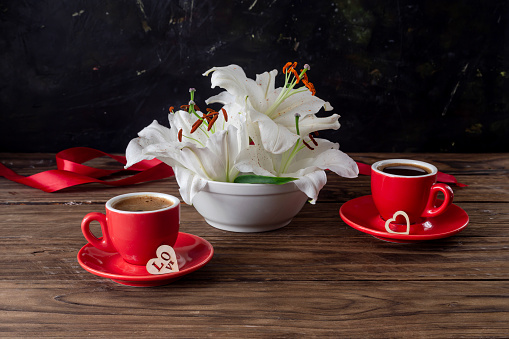 Valentine's Day decorations. Still life to day Valentine with red cups of coffee and white lilieson the table close-up