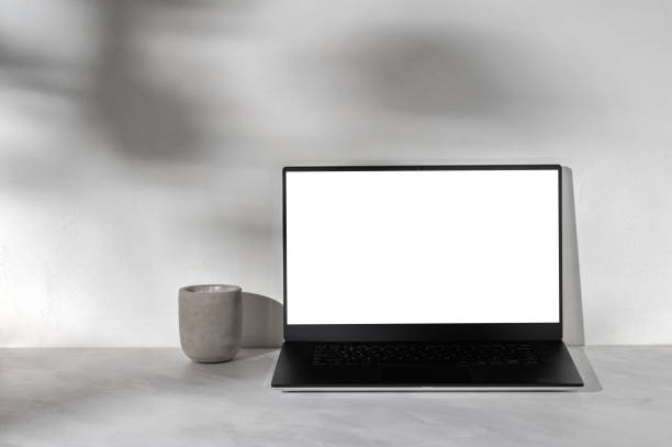 istock Laptop computer with blank white display mockup, concrete candle on neutral gray marble desk background, white plaster wall with abstract sun light shadows, lifestyle home office workspace template 1987571014