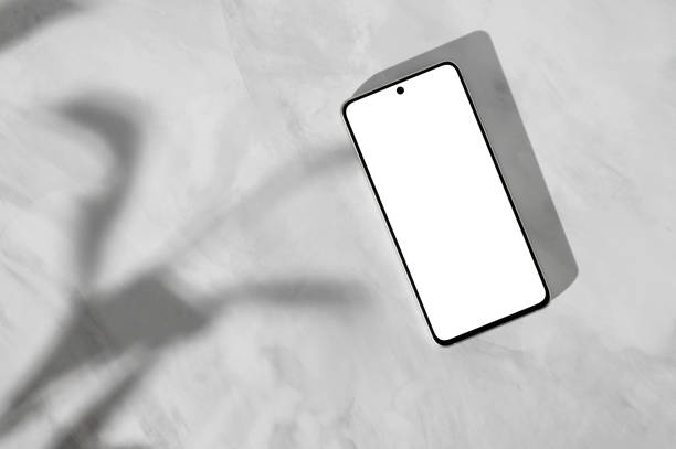 istock Mobile phone with blank white screen mockup on neutral gray marble desk with aesthetic abstract floral sunlight shadows, minimal social media blog template, flat lay 1987572101