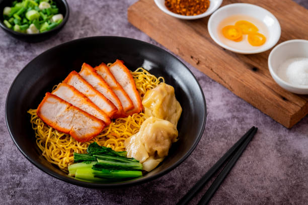 istock Egg noodle with red roasted pork and wonton in black bowl 1987572138