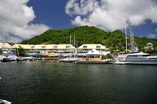 Marigot, Collectivity of Saint Martin, French Caribbean: Marina Port Royal harbormaster building - in the background restaurants, offices and shops along Rue du President Kennedy and hills covered in tropical vegetation.