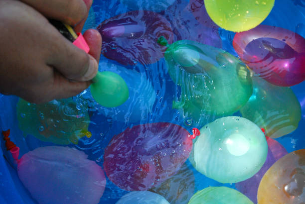 istock Hands filling small, colorful water balloons. 1987600123