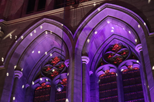 Stone window arches inside an old church illuminated at night by purple lights