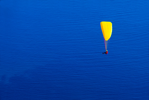 yellow paraglider over the blue water of the Cote d Azur, Menton, Département Alpes-Maritimes, France
