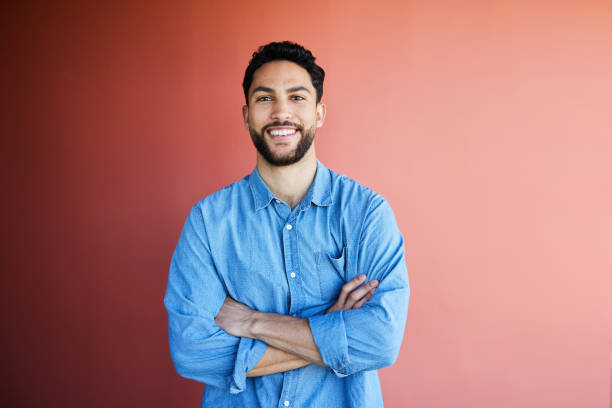 Young businessman smiling while standing against a red office wall