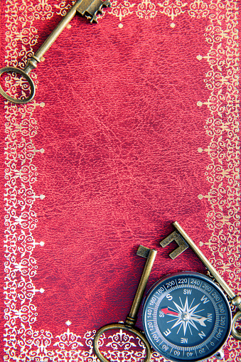 The key and compass on old book background.
