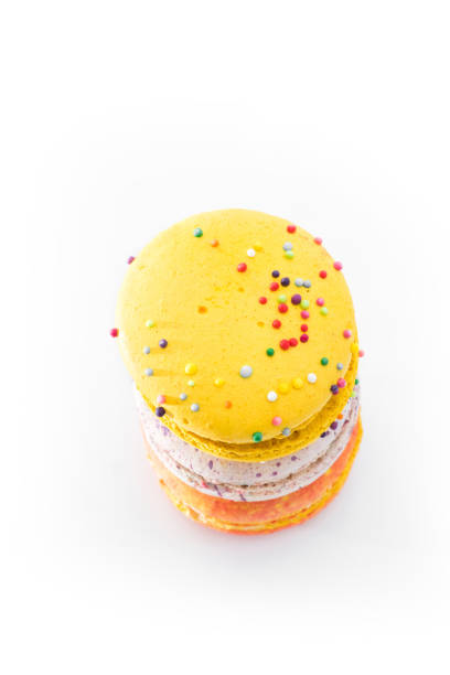 Sweet yummy macarons isolated on white background. Brightly colorful stacked macaroons. Three tasty multi-colored orange, pink and yellow macaroons. French pastry made from egg whites.