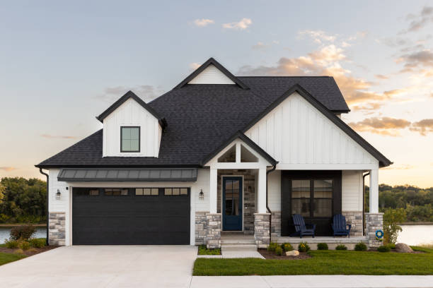 A black and white luxury home with a sunset. Elmhurst, IL, USA - September 25, 2022: A black and white luxury home with a two car garage and black door, professional landscaping, and a lake in the background at sunset. empty home garage stock pictures, royalty-free photos & images