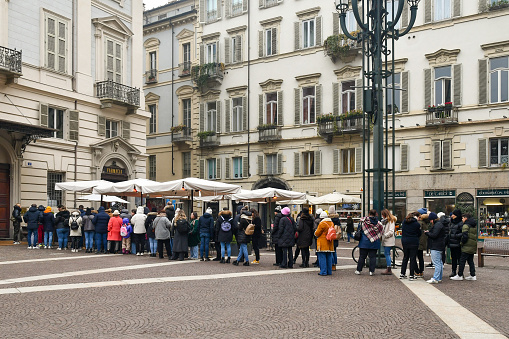 Turin, Piedmont, Italy - 12 09 2023: People queuing to enter a famous pastry shop in the historic centre of Turin, in autumn.