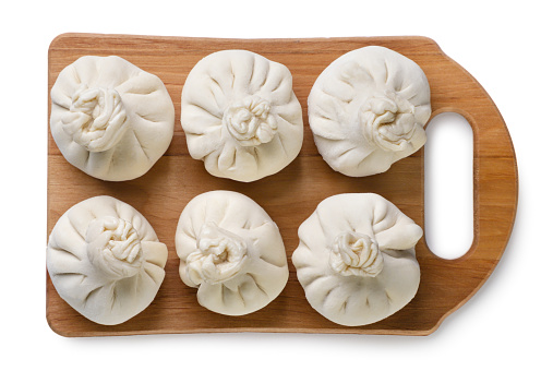 Khinkali on a wooden board close-up on a white background. Top view