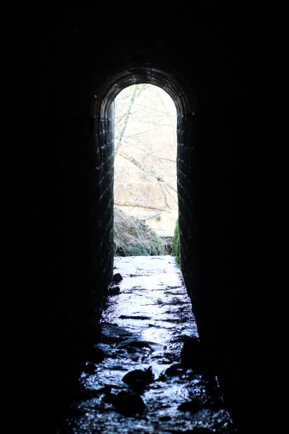 istock View through an arched tunnel carrying a stream beneath a bridge 1987641173
