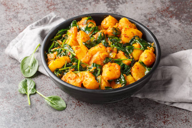 istock Saag aloo is a classic Indian style side dish featuring potatoes fried in spices and spinach closeup on the bowl. Horizontal 1987655682