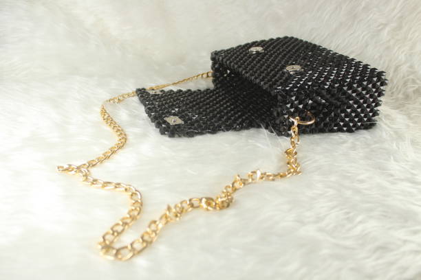 istock Handmade black purse made with bright beads on white furry blanket with gold handle. Isolated on white. 1987657315