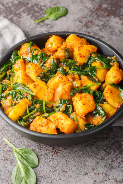 istock Spiced curry dish made with potatoes and spinach saag aloo closeup on the plate. Vertical 1987659461