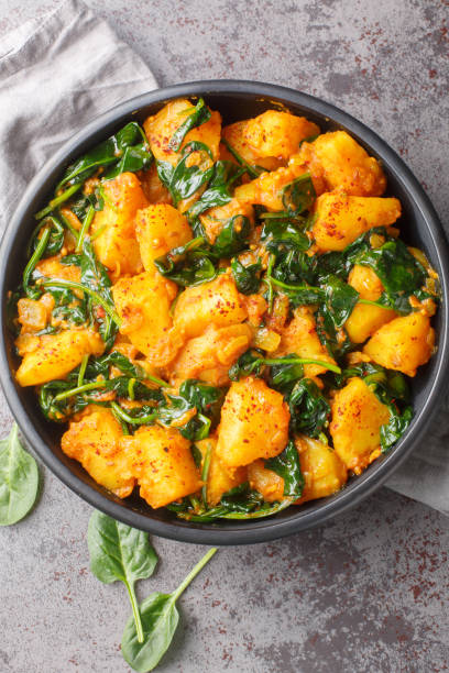 istock Spiced curry dish made with potatoes and spinach saag aloo closeup on the plate. Vertical top view 1987660004
