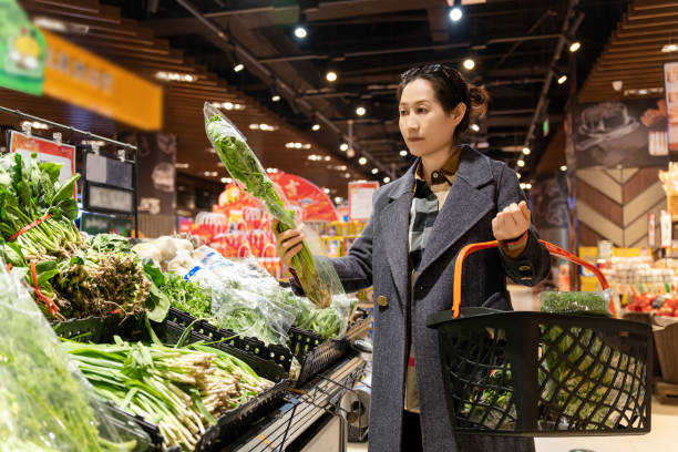istock Confident Woman Selecting Fresh Vegetables at Supermarket 1987660539