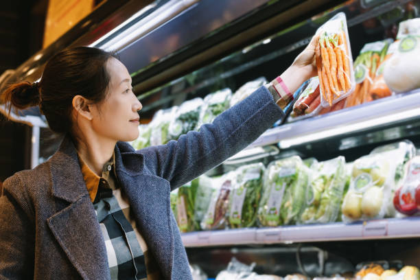 istock Woman Selecting Fresh Carrots at Grocery Store 1987662140