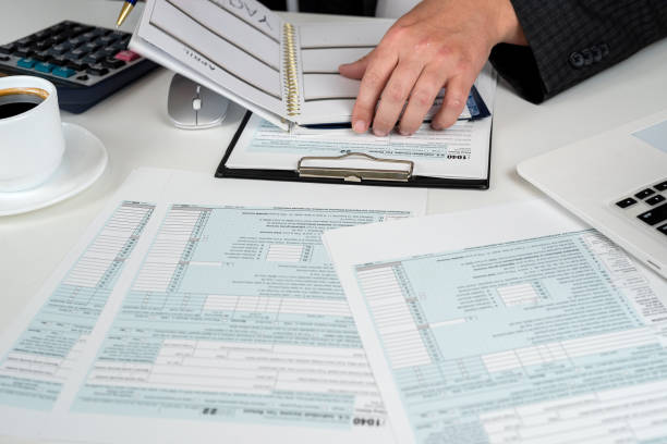 istock man completing tax form 1040. Tax time 1987666475