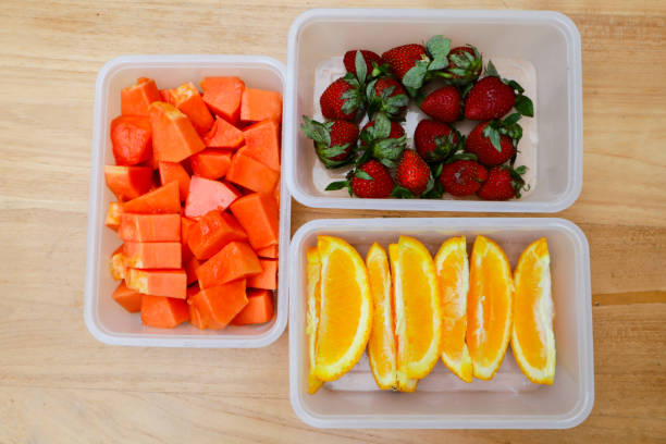 istock plastic containers containing papaya, strawberries and oranges, on a wooden background 1987672402
