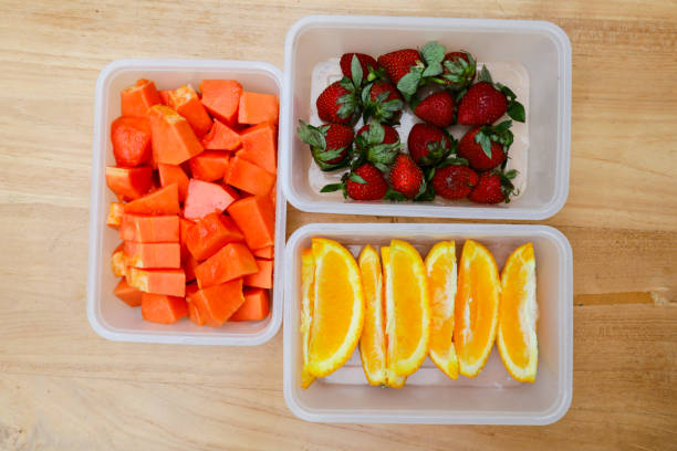 istock plastic containers containing papaya, strawberries and oranges, on a wooden background 1987676059